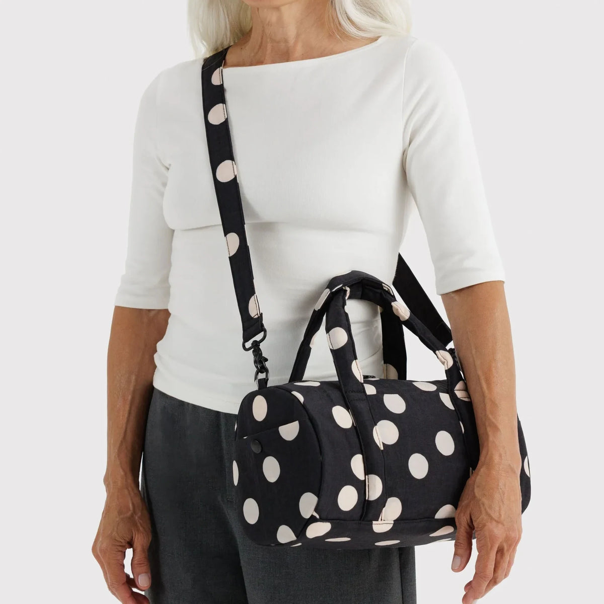 Polka-dot nylon duffle bag worn crossbody, black handles and adjustable strap