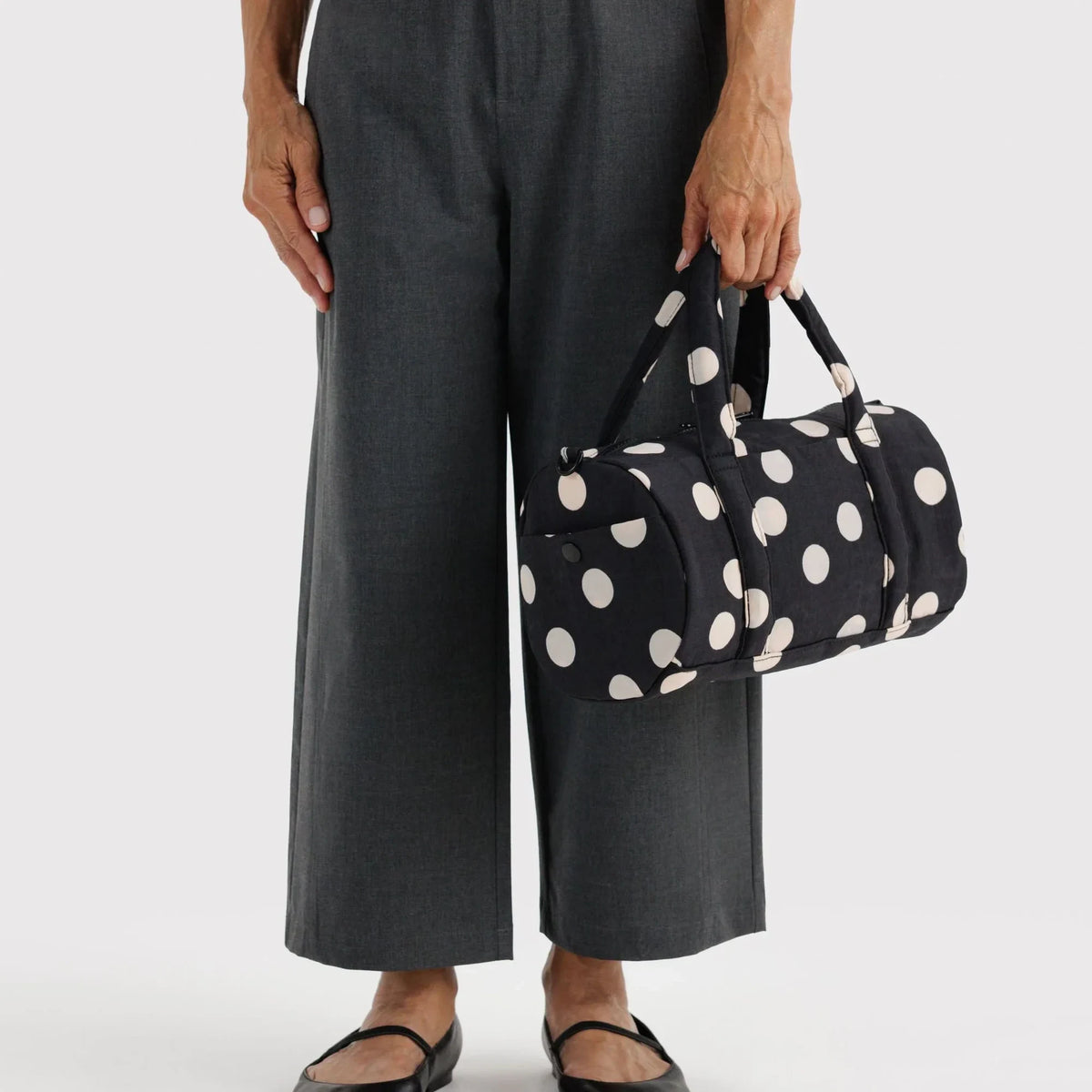 Polka-dot nylon duffle bag with short handles and crossbody strap, side view