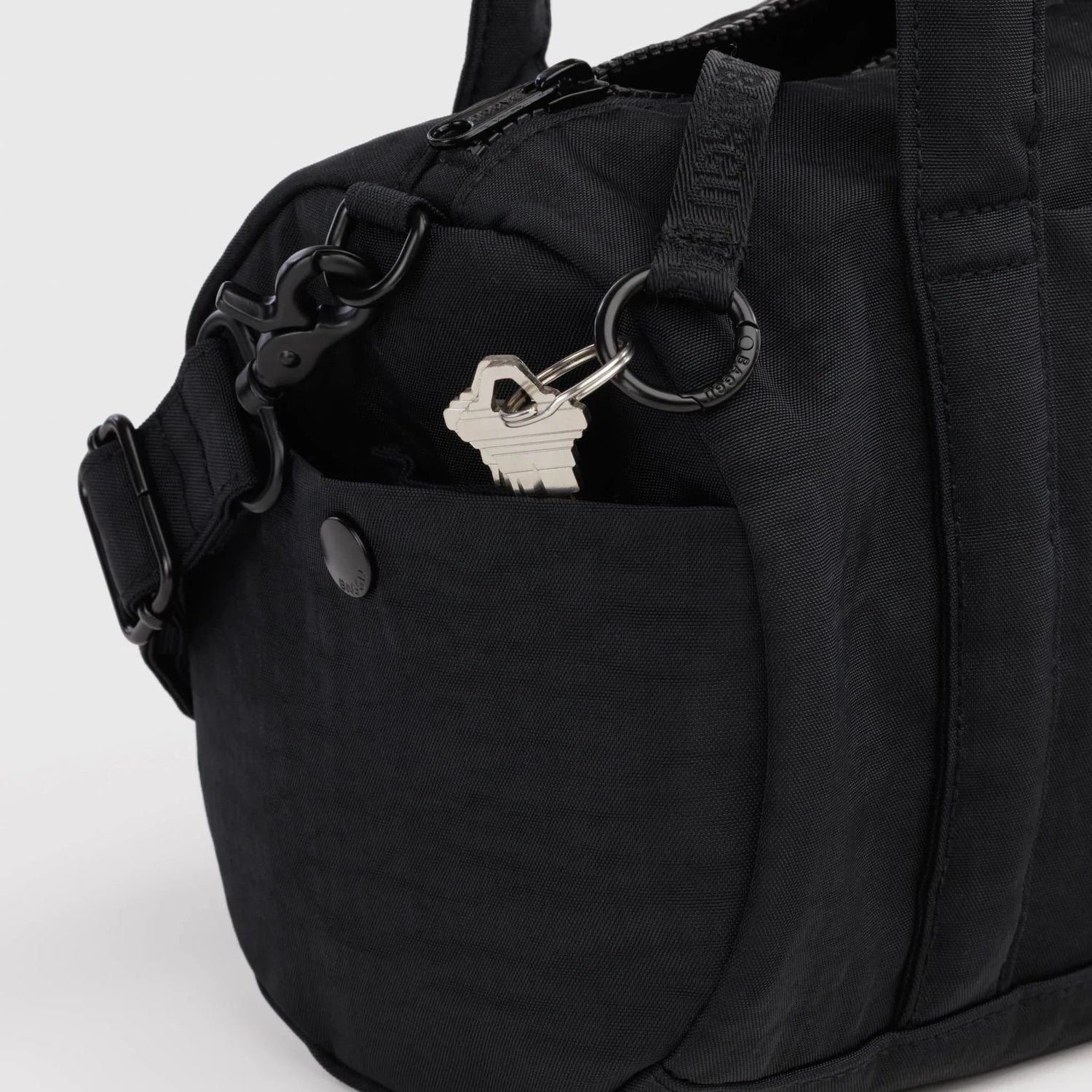 Black nylon duffle bag with front snap pocket and metal D-ring key holder