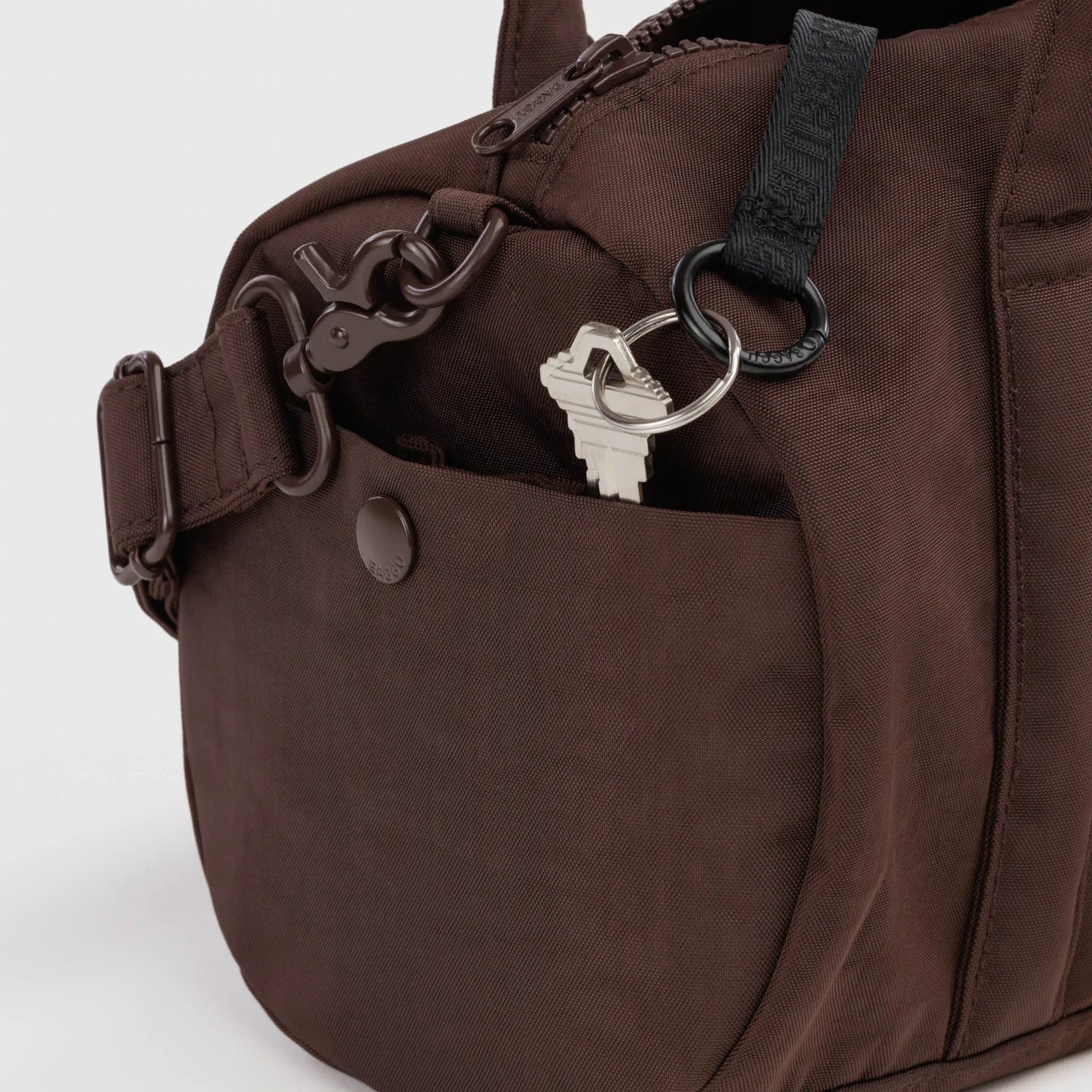 Coffee-brown duffle bag with key clip, metal rings, and zip front pocket