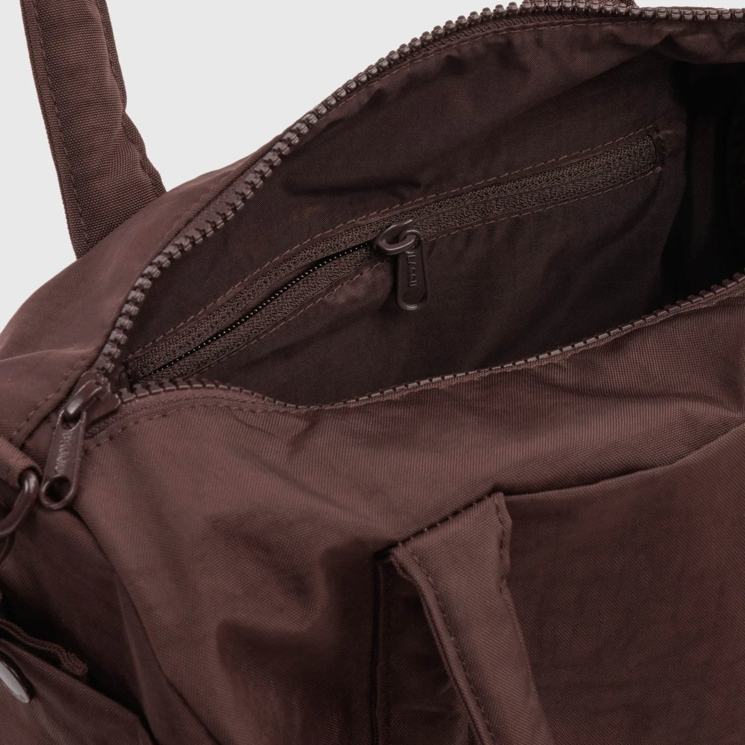 Coffee-brown duffle bag interior with zippered pocket and stitched seams