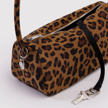 Brown leopard print cylindrical shoulder bag with silver zipper and black strap holding keys on white background