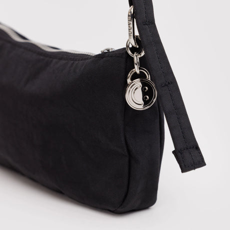 Black nylon pochette bag side view with metal rings and webbing strap