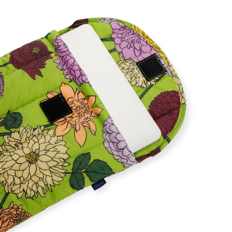 The Baggu Puffy Laptop Sleeve for 13"/14" laptops, designed by Baggu, offers an eco-friendly floral-patterned green fabric with a delightful dahlia print and a secure Velcro closure.