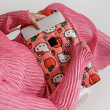 A person holding a Hello Kitty x Baggu Laptop Sleeve in pink, designed for 13"/14" devices and featuring strawberries and apples with a theme of recycled materials, while wearing a pink pleated outfit.