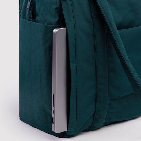 Teal fabric bag side pocket holding a slim silver laptop against a plain light background