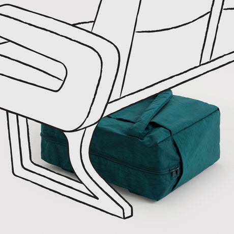 Teal fabric compact travel bag with zipper and handle placed under seat frame on light background