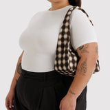 Small nylon shoulder bag with blurred brown gingham, worn on shoulder
