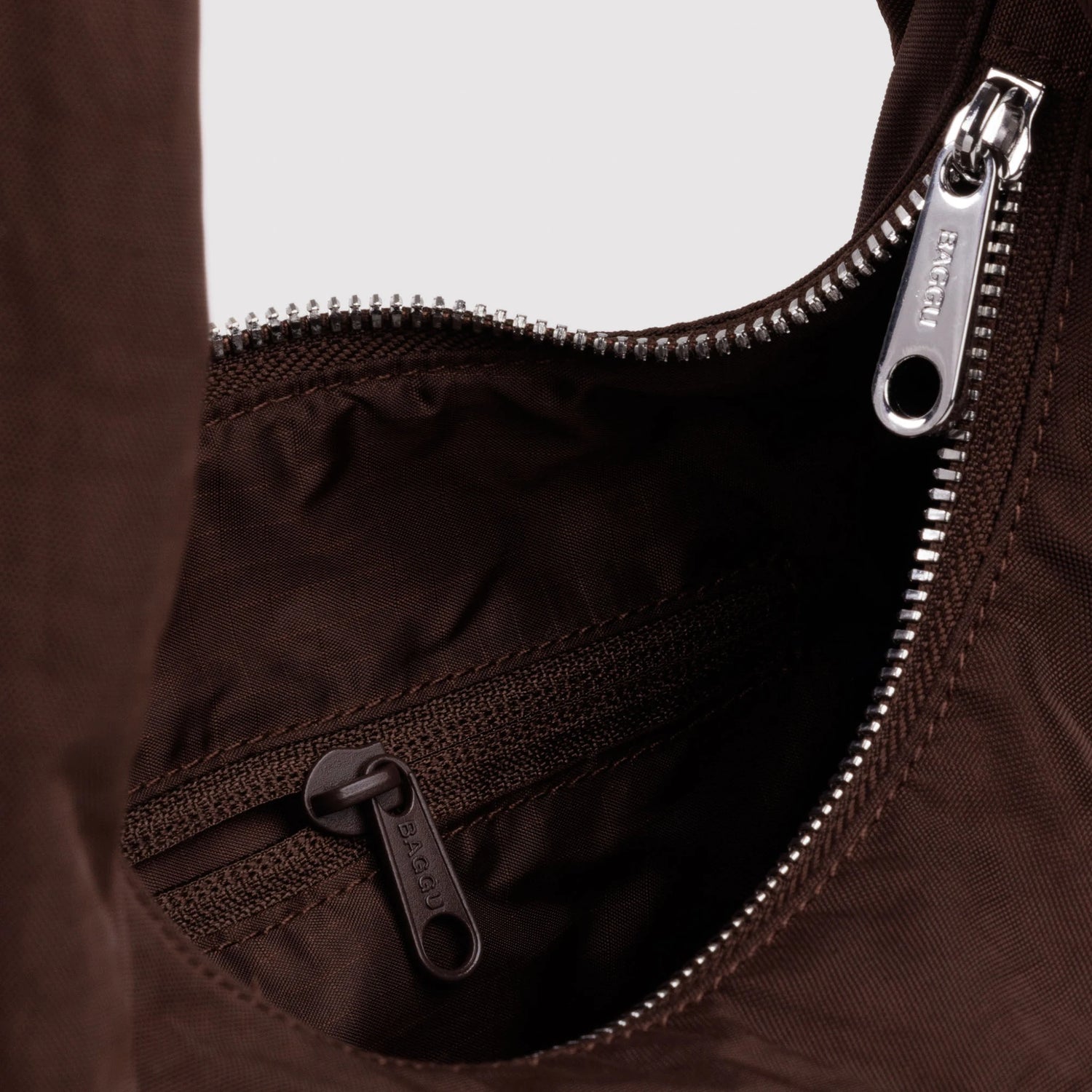 Close-up of coffee-brown nylon bag interior with zip pocket and zipper pull