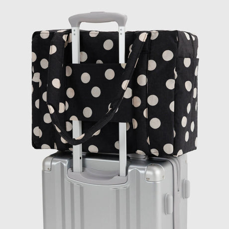 Polka-dot tote bag with cream dots, secured over a carry-on suitcase