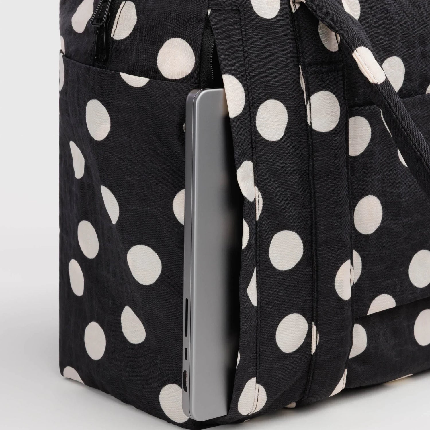 Black polka-dot tote bag with cream dots, zipper panel and carry-on sleeve