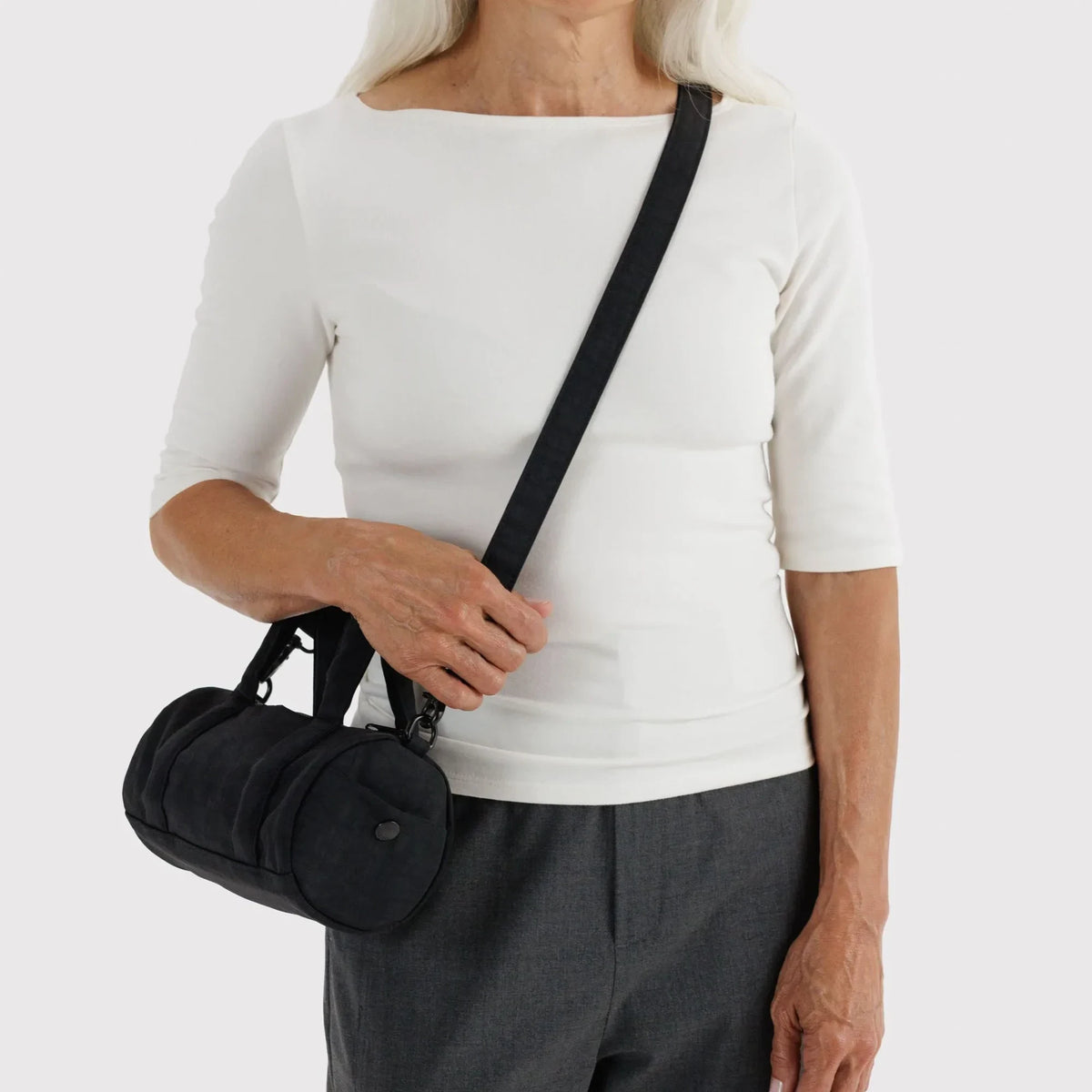 Black small duffle bag worn crossbody with adjustable strap