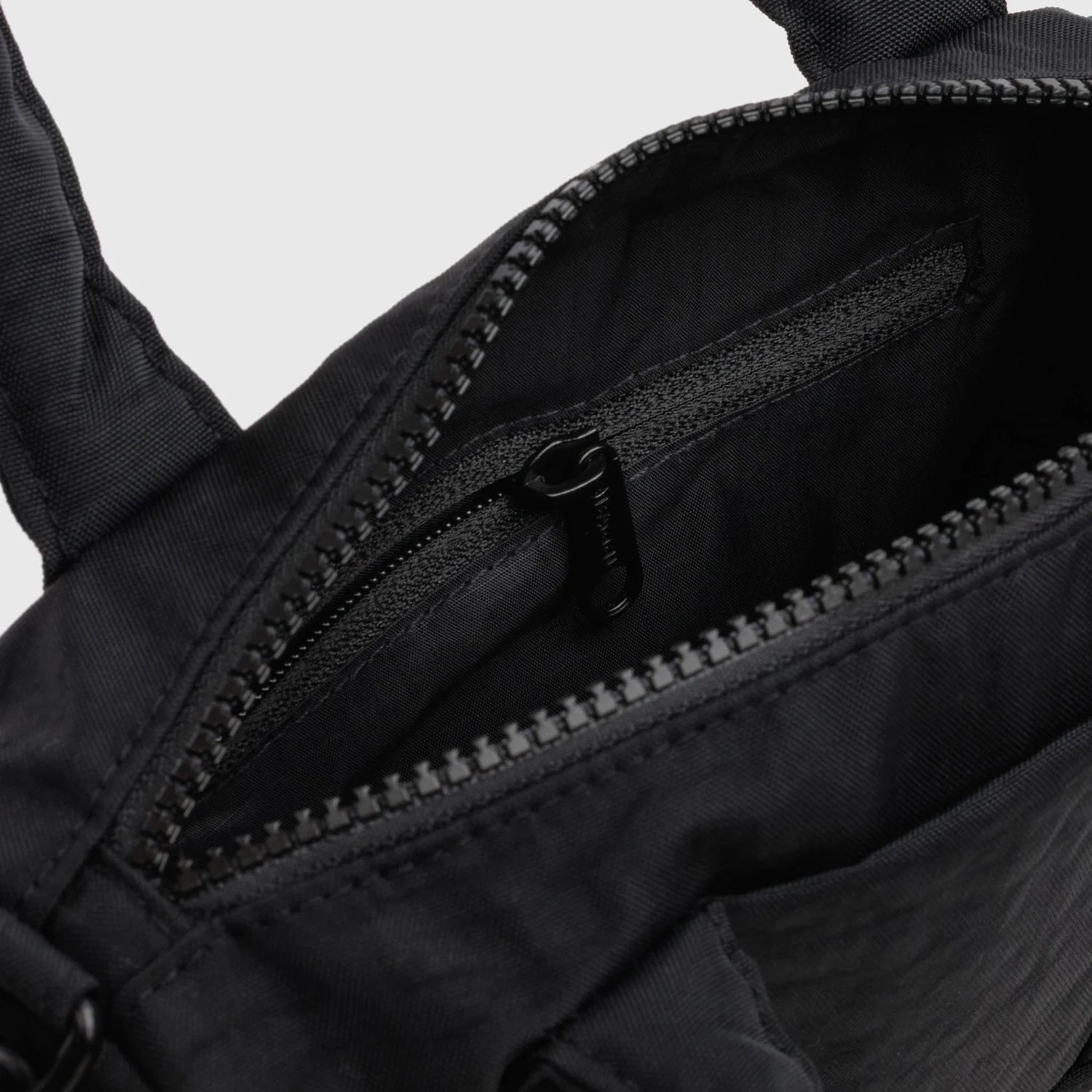 Black nylon duffle bag interior close-up with zip track and lining