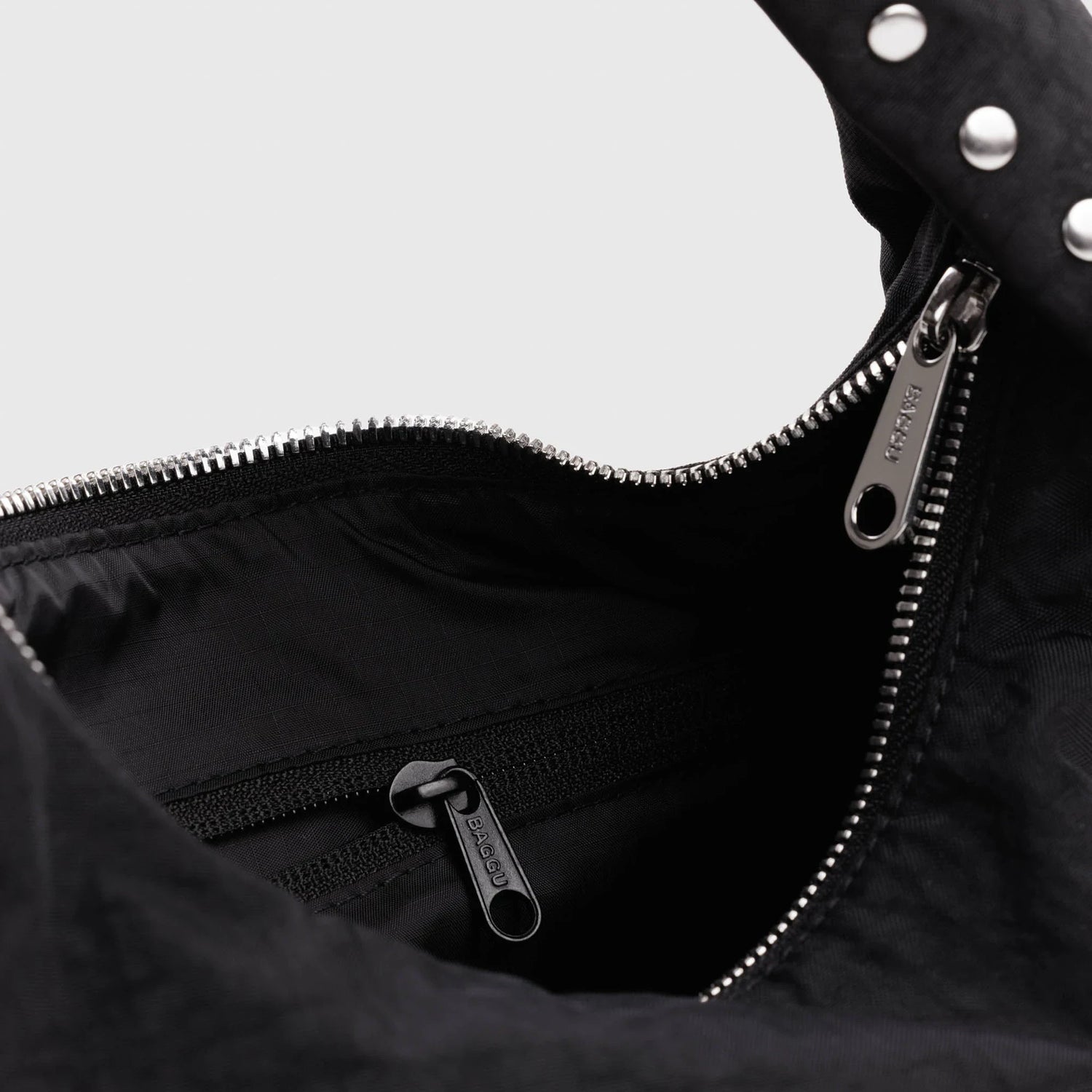 Black nylon bag interior with zipper and metal pull at top opening