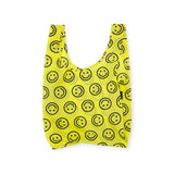 The Baggu Standard Reusable Bag in yellow showcases a cheerful smiley face design, reflecting its sustainable nature.