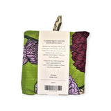 The Baggu Standard Reusable Bag - Dahlia by Baggu is a sustainable option featuring a folded design with a vibrant floral print set against a green backdrop. Made from recycled nylon, it includes an attached tag that highlights its eco-friendly features and practical uses.