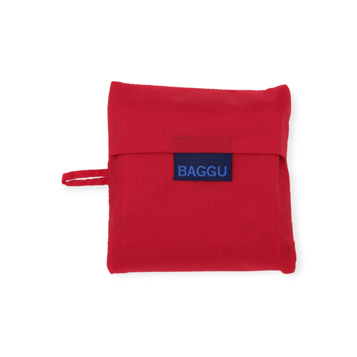 The Baggu Standard Reusable Bag in Candy Apple is a foldable, eco-friendly tote made from recycled nylon, featuring a snap closure and a convenient small loop on the side.