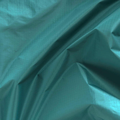 Close-up of crumpled, malachite-colored fabric with visible texture and folds, meticulously crafted from recycled nylon, featuring the Baggu Standard Reusable Bag in Malachite by Baggu.