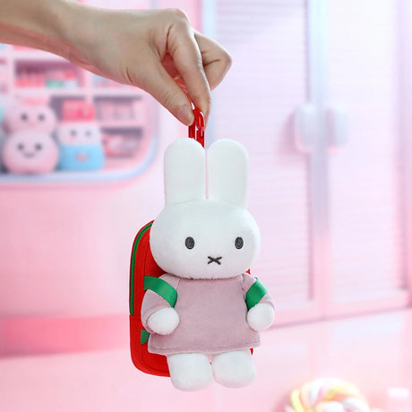 Hand holding plush bunny mini backpack keychain with red clasp