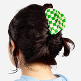 Green and white checkered claw clip worn in hair, side view