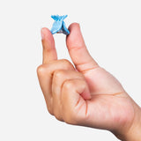 Single small blue micro claw hair clip held between fingers.