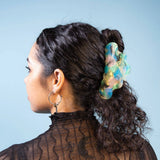 Translucent aqua-green jelly claw clip on dark hair bun, side view