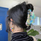 Jelly claw hair clip holding dark hair in a bun; translucent aqua-green color