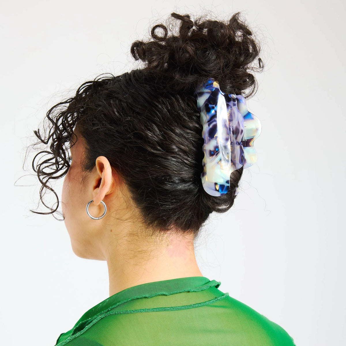 Claw hair clip on short curly hair, translucent milk-jelly with blue-purple swirl pattern.
