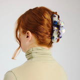 Hair claw clip fastened on a bun, translucent milk-jelly with blue and purple marbling.