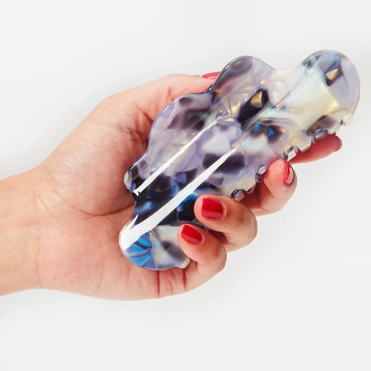 Claw hair clip in translucent milk-jelly color with purple-blue pattern, held in hand.