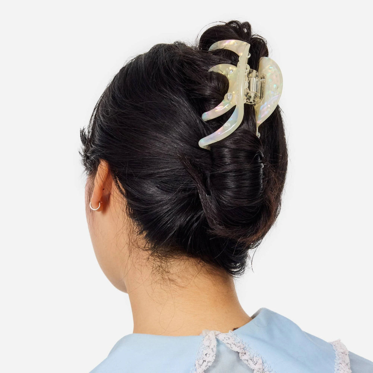 Large iridescent octopus-claw hair clip clipped into wavy dark hair