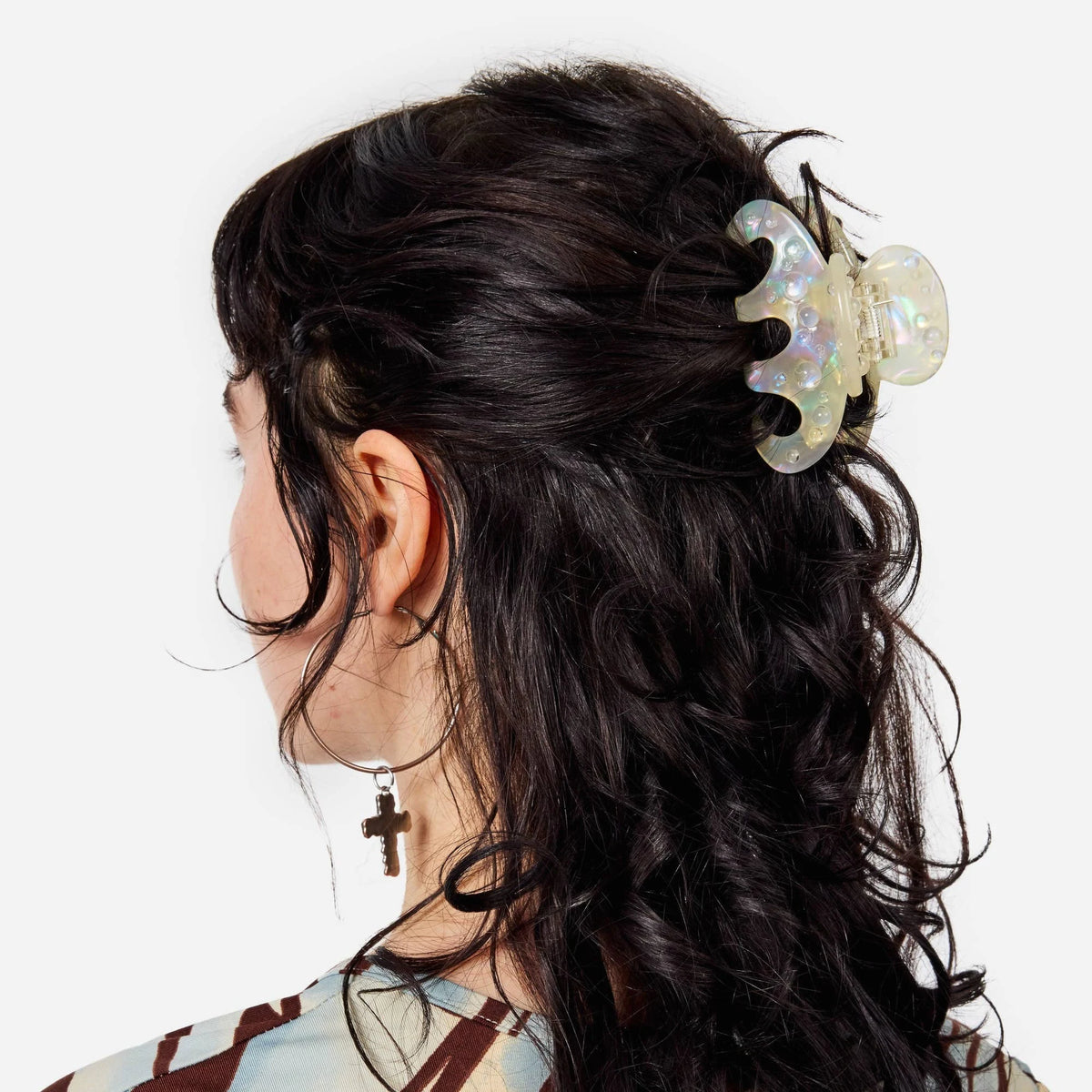 Octopus claw hair clip with pearl-shimmer finish on dark hair, side view.