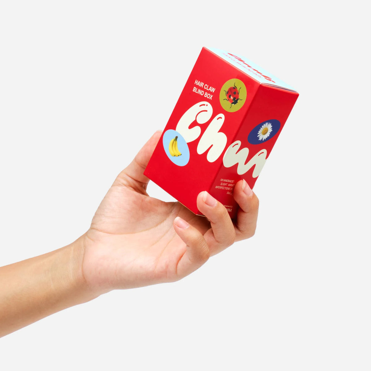 Hair claw clip blind box packaging held in hands, red box with character icons