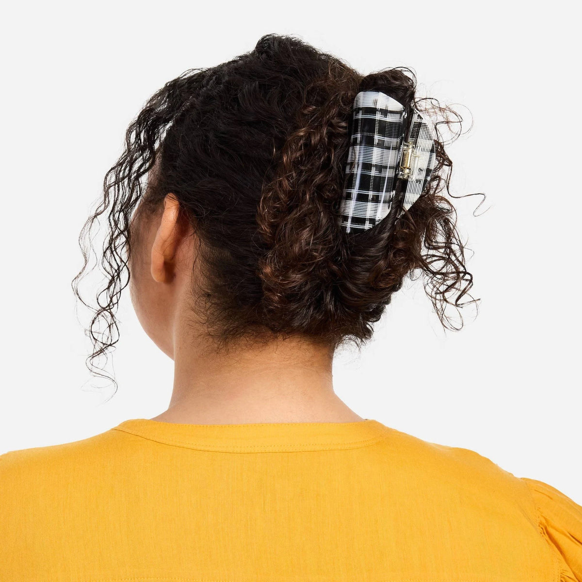 Black-and-white plaid claw clip securing curly hair at the back of the head