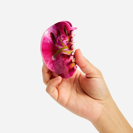 Pink lily claw hair clip held open, showing gold-toned inner teeth