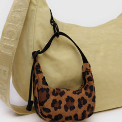 Leopard print mini bag attached to a larger beige shoulder bag with a logo strap.