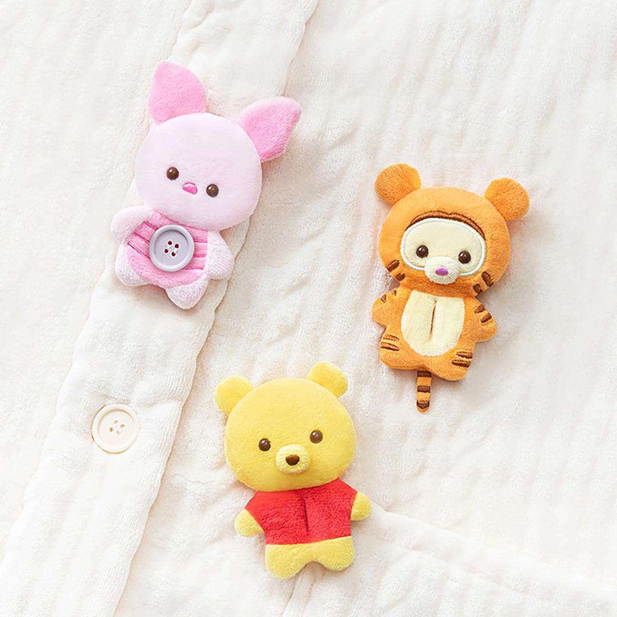 Three plush animal charms: pink rabbit, orange tiger, and yellow bear, each with button details.
