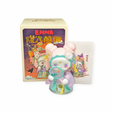 A collectible figurine with pastel colors and floral decorations stands in front of a matching box labeled "Lucky EMMA - Secret Forest of Dim Lights Series Blind Box," evoking the thrill of discovering a treasure from a Secret Forest.