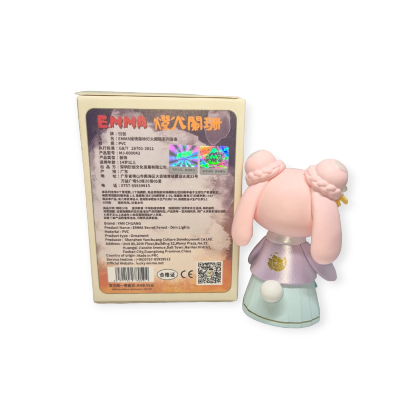 A box adorned with text and a holographic sticker is placed next to Lucky EMMA, a figurine featuring pink hair and a pastel green and purple outfit, derived from the captivating Secret Forest of Dim Lights Series Blind Box by Lucky Emma.