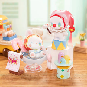 Two pastel toy figures—a mouse in an ice cream bowl and a clown with a lollipop—are displayed with playful props and the Lucky Emma Emma Fairy Babe Academy Blind Box, perfect for magical school collectible fans.