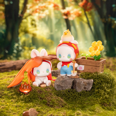 Chibi collectible figures: orange-cape character and blue-shirt character by a flower box
