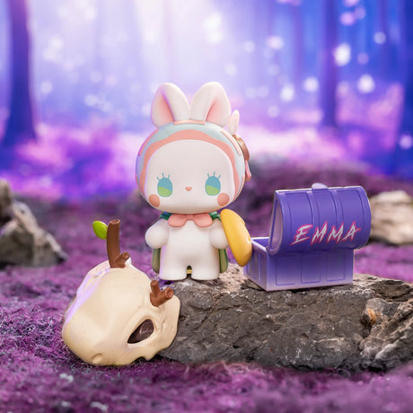 Chibi collectible figure holding a purple EMMA watering can by a white skull prop