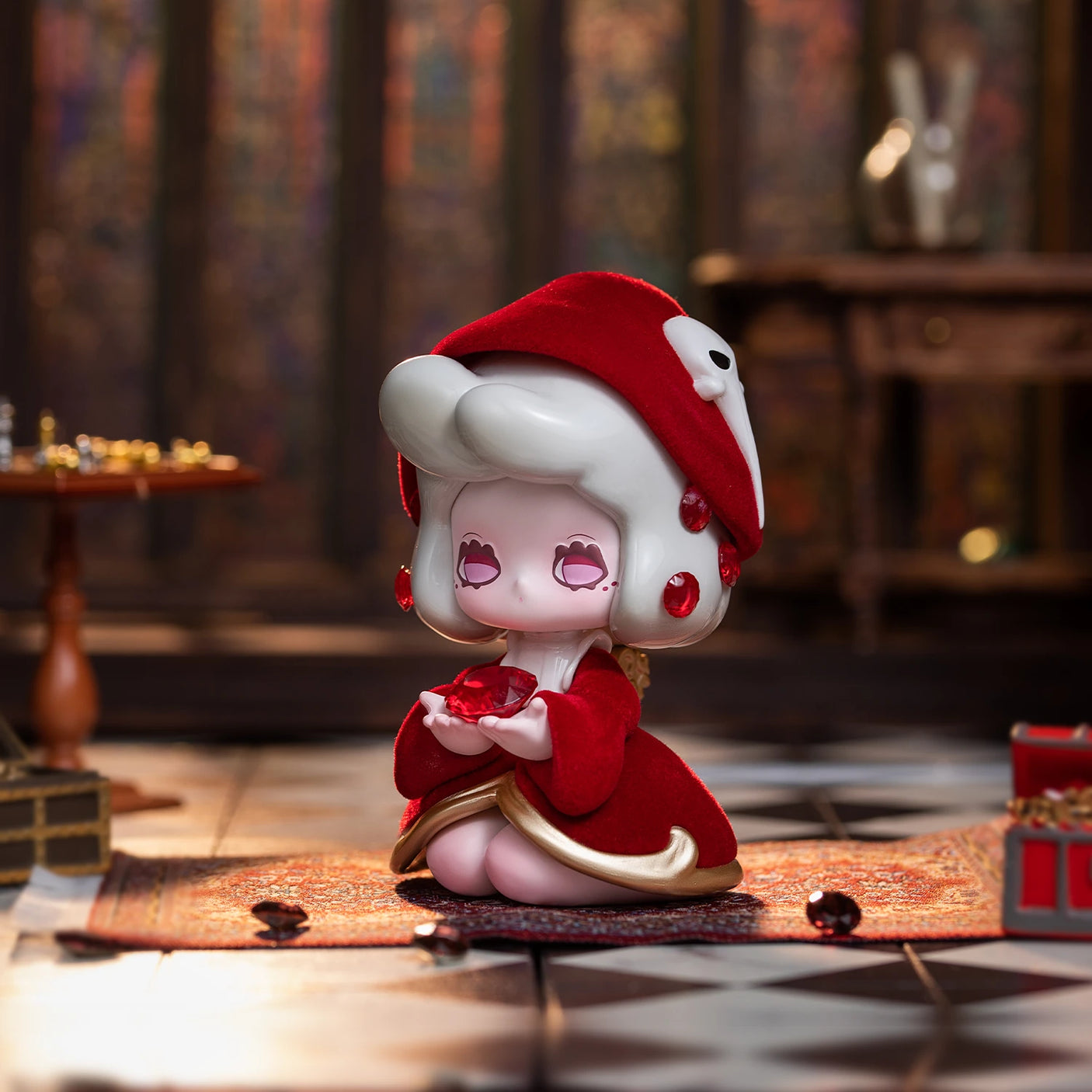 A charming figurine with red and white details is displayed on a patterned rug, reminiscent of a Lucky EMMA - Killa Treasure Pavilion Blind Box item. The scene features a wooden table and checkered floor in the background, enhancing the allure of this Secret Treasures setting from Lucky Emma.