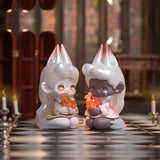 Two fantasy figures with white hair kneel, holding translucent orange flames, as if unveiling secret treasures. They are surrounded by lit candles on a checkered floor, with stained glass windows casting colorful light reminiscent of the enchanting allure of the Lucky EMMA - Killa Treasure Pavilion Blind Box.