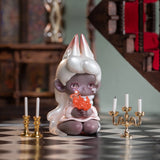 A small figurine with pointed ears and white hair, named Lucky EMMA, cradles an orange flame and is perched between two gold candelabras on a black and white checkered floor—evoking the hidden wonders of the Lucky Emma's Killa Treasure Pavilion Blind Box.