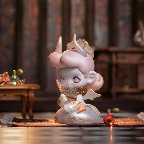 A small figurine from the Lucky EMMA - Killa Treasure Pavilion Blind Box, complete with horns and wings, rests on a carpet while holding a large crystal like a hidden gem. The room features a table and small decorative bottles in the background, reminiscent of whispers of secret treasures from Lucky Emma.