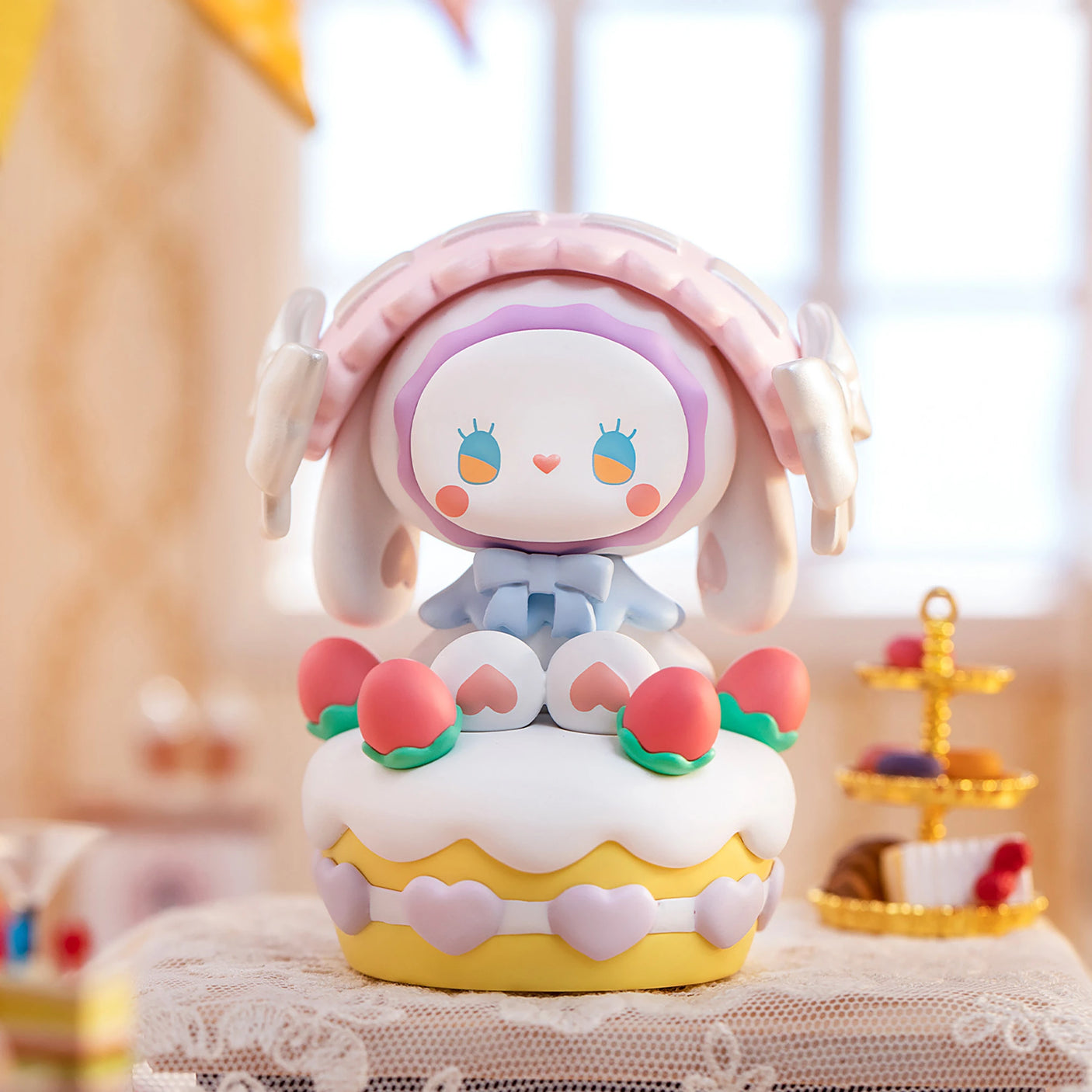 At the Secret Forest Birthday Party, a charming Lucky EMMA - Secret Forest Birthday Party Blind Box figurine from the Lucky Emma brand, featuring a pastel color scheme, adorns a decorative cake and is surrounded by pink and peach accents.