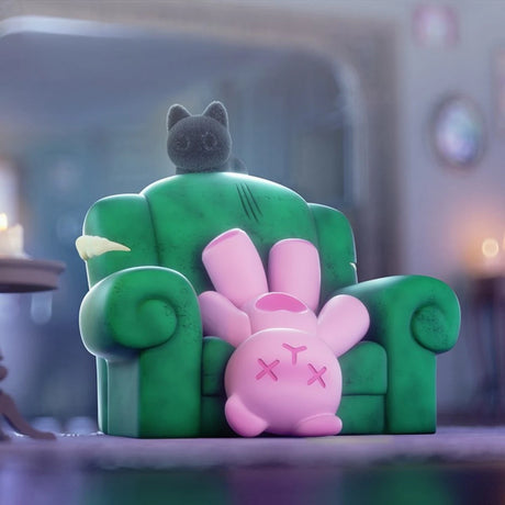 Pink ShinWoo Ghost Bear figure lying upside down on worn green armchair with small black cat figure on top in dim room