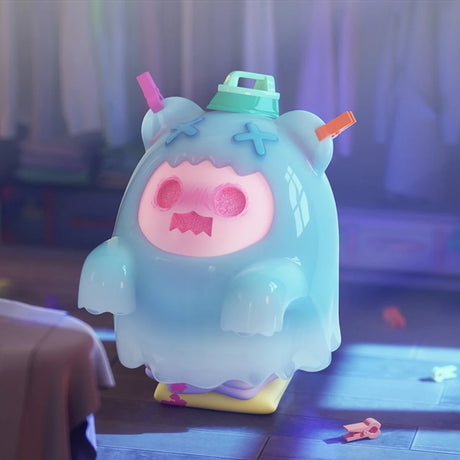Glossy pastel blue ShinWoo Ghost Bear figure with pink face and crossed eyes standing on purple and yellow base in soft room light