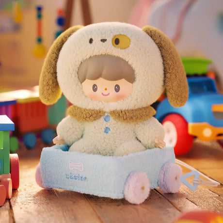 Cute plush keychain character wearing a fluffy dog hood sitting in a blue toy car on wooden floor